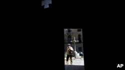 ARCHIVO-Una mujer, enmarcada por una puerta de la Iglesia Católica Merced, pasa en La Paz, Bolivia, el martes 2 de mayo de 2023. 