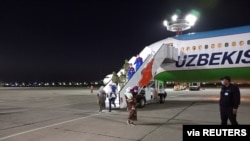 Para penumpan turun dari pesawat setelah tiba di Tashkent, Uzbekistan, dari Suriah, 30 April 2021. Uzbekistan memulangkan perempuan dan anak-anak dari Suriah yang sebelumnya tinggal di kamp-kamp untuk keluarga mantan kombatan ISIS.