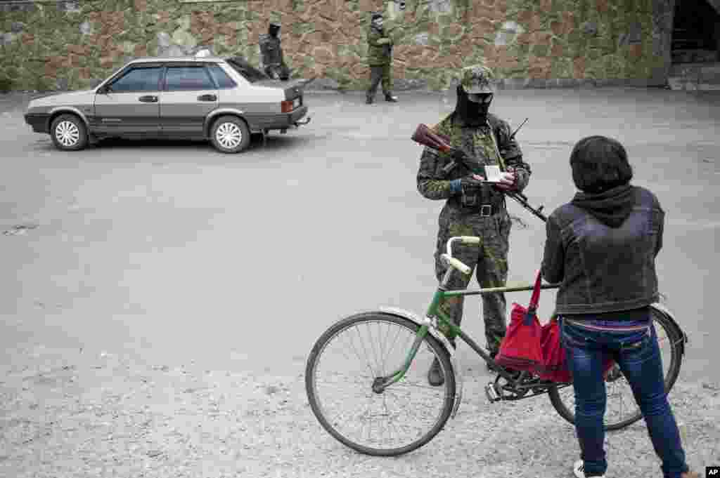 A pro-Russian fighter checks documents of a woman leaving the city at a checkpoint in Slovyansk, eastern Ukraine, June 12, 2014.
