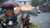 Los vendedores ambulantes se protegen de la lluvia de la tormenta tropical Laura en Puerto Príncipe, Haití, el domingo 23 de agosto de 2020. 