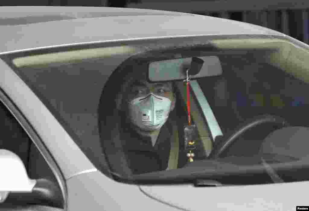 A man wearing a mask drives a car amid thick haze in the morning in Beijing, Feb. 26, 2014. 