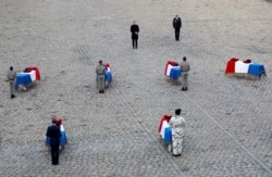 French President Emmanuel Macron pays his respect in front of the flag-draped coffins of the thirteen French soldiers killed in Mali, during a ceremony at the Hotel National des Invalides in Paris, Dec. 2, 2019.