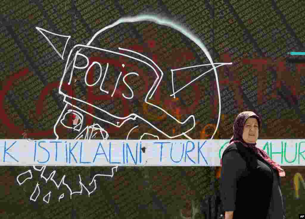 Seorang perempuan melewati grafiti bertuliskan "Kemerdekaan Turki" di Alun-Alun Taksim, Istanbul (3/6). (AP/Thanassis Stavrakis) 