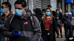 FILE - People in Brooklyn's Sunset Park, a neighborhood with one of the New York's largest Mexican and Hispanic community, wear masks to protect against the coronavirus while waiting in line to enter a store, May 5, 2020, in New York.