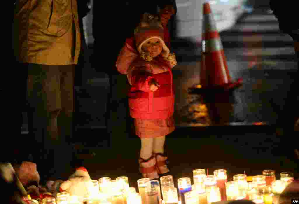 2012年12月16日,人們在一處臨時紀念龕憑吊小學槍擊案遇難者,一位男孩手指著蠟燭。