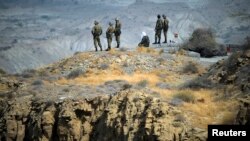 FILE - Members of Iran's Revolutionary guard monitor an area as they stand on a hill top in the Hormuz area of southern Iran, April 24, 2010.