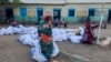 Une femme déplacée porte des sacs de l'aide humanitaire dans un camp à Gadaref, le 12 mai 2024.