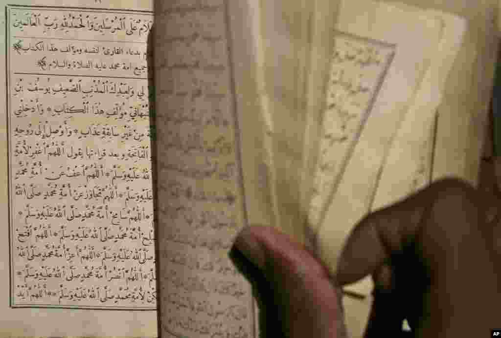 This March 16, 2004 shows Alhousseini Ould Alfadrou, 16, singing verses from crumbling ancient Islamic manuscripts in a mud-walled house in Timbuktu, Mali.
