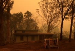 Evan Harris owns this mud brick house, where he prepared to minimize fire impact at Burragate, Australia, Jan. 10, 2020, as a nearby fire threatens the area.