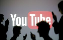 FILE - Silhouettes are seen in front of a Youtube logo, in this picture illustration taken in Zenica, Oct. 29, 2014.