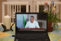 Hungarian Prime Minister Viktor Orban is seen on a laptop screen in a flat in Budapest as he makes an April 9, 2020, announcement that the government extended the partial curfew for an indefinite time in Budapest.
