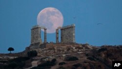 Burung camar terlihat terbang di angkasa, saat bulan purnama menyinari bumi dari balik marmer kuil kuno Poseidon di Cape Sounion, sebelah tenggara Athena, 20 Juni 2016 (Foto: dok).