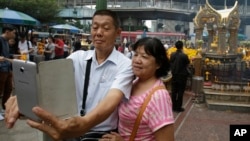 Asian tourists takes a "selfie" in front of the Erawan Shrine in Bangkok, Thailand, Oct. 22, 2015.