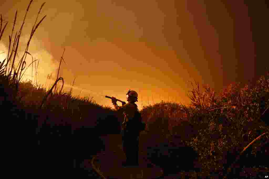 Firefighter Ryan Spencer battles a wildfire as it burns along a hillside toward homes in La Conchita, California, Dec. 7, 2017.