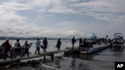 Migrantes abordan el barco hacia el Tapón del Darién, en Necoclí, Colombia, el sábado 7 de octubre de 2023.