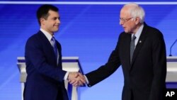 FILE - Democratic presidential candidates Pete Buttigieg, left, and Bernie Sanders shake hands on stage, Feb. 7, 2020, before the start of a Democratic presidential primary debate at Saint Anselm College in Manchester, N.H.
