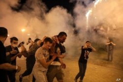 Manifestantes huyen de los gases lacrimógenos lanzados por la policía durante las protestas por los resultados anunciados de las elecciones.