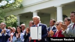 El presidente Donald Trump posa con el decreto sobre la Iniciativa para la Prosperidad Hispana de la Casa Blanca instantes después de firmar el documento.