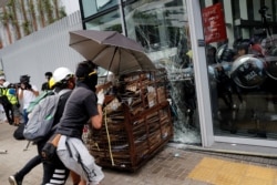 FILE - Protesters try to break into the Legislative Council building in Hong Kong where riot police are seen, during the anniversary of Hong Kong's handover to China, July 1, 2019.