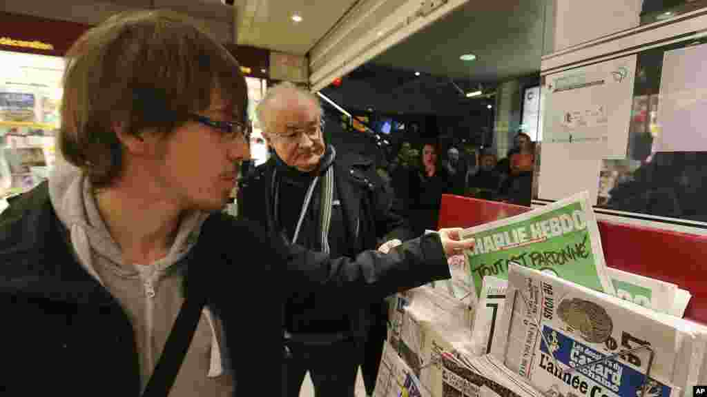 A man picks up a copy of Charlie Hebdo newspaper at a newsstand in Rennes, western France, Jan. 14, 2015.