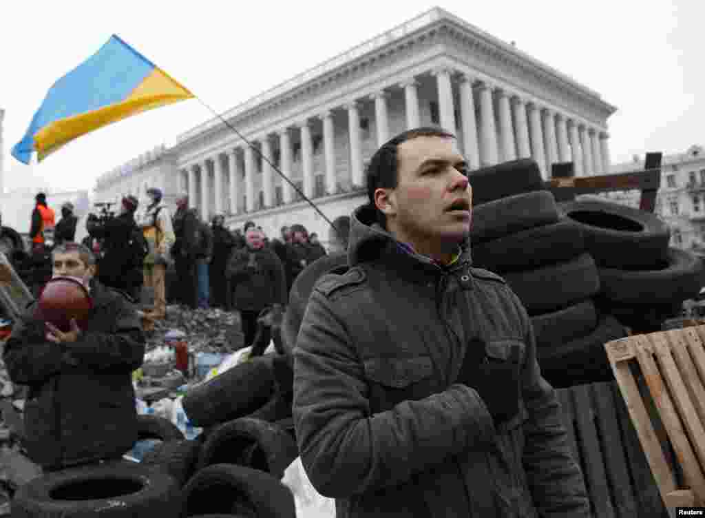Anti-government protesters sing the national anthem as they gather at a barricade, central Kyiv, Feb. 19, 2014.