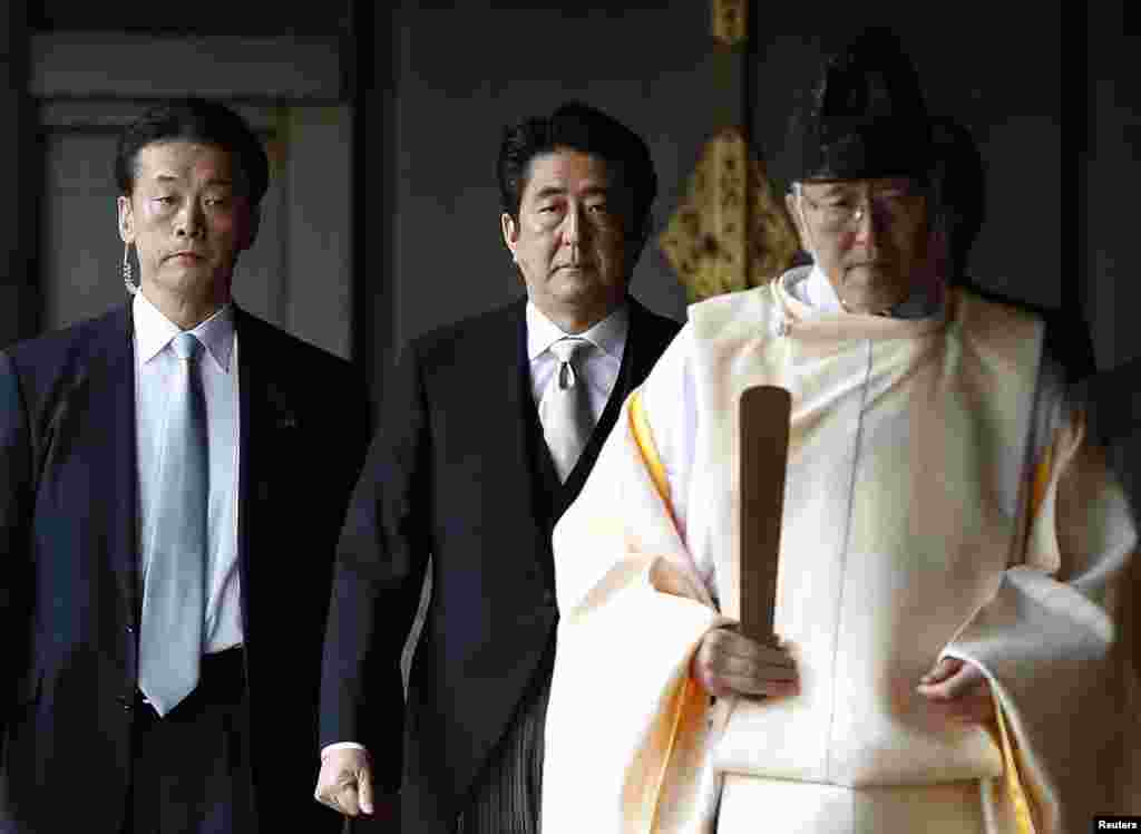 Japan's Prime Minister Shinzo Abe follows a Shinto priest as he visits Yasukuni Shrine in Tokyo, Dec. 26, 2013.