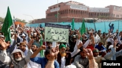 Pendukung dari partai politik Islamis Pakistan, Tehreek-e-Labaik, memegang sebuah tanda dalam bahasa Urdu yang artinya, "Singkirkan Zahid Hamid" saat melakukan aksi unjuk rasa di sepanjang jalan utama di Karachi, 27 November 2017.