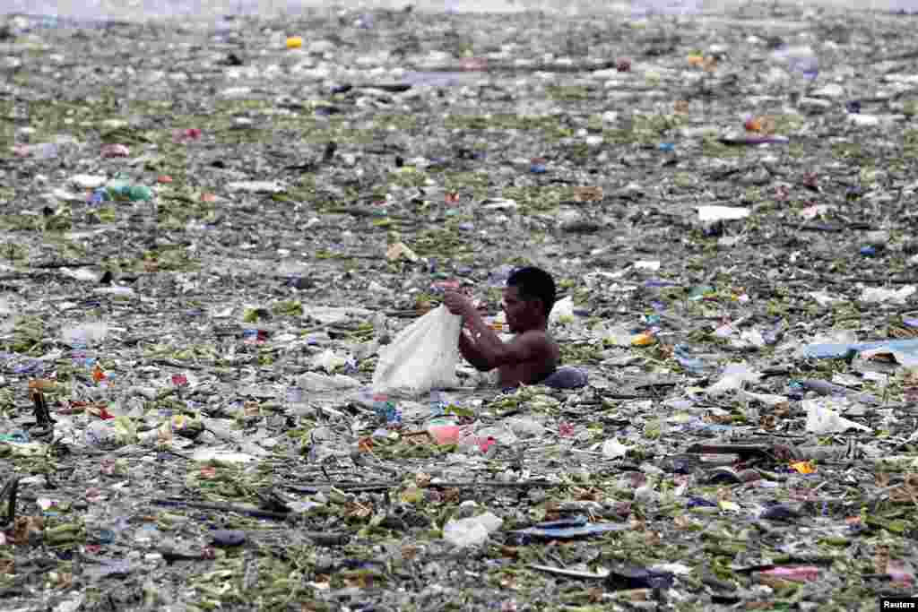 Một người Philippines thu nhặt plastic và các món có thể tái chế trong đám rác đổ ra vịnh Manila sau bão Saola, 30/7/2012.