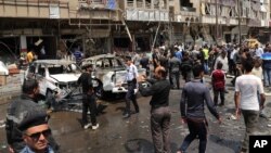 Pasukan keamanan dan warga Irak memeriksa lokasi serangan bom mobil di distrik Karrada, Baghdad, Sabtu (9/5).