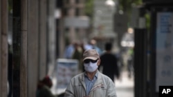 Un hombre con un tapabocas para combatir la propagación del coronavirus espera para ingresar a una tienda en Madrid, España, el jueves 7 de mayo de 2020.