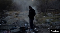 Krijumčar (koje inače nazivaju kojotima) se grije pored vatre na Božićno jutro, nakon što je grupu imigranata ilegalno iz Meksika preveo u Igl Pes u državi Teksas.