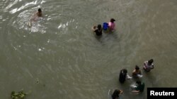 Migrantes lavan ropa en el río Grande cerca de un improvisado campamento ocupado por solicitantes de asilo en el puente internacional Gateway en Matamoros, Tamalipas, México, el 28 de octubre de 2019.