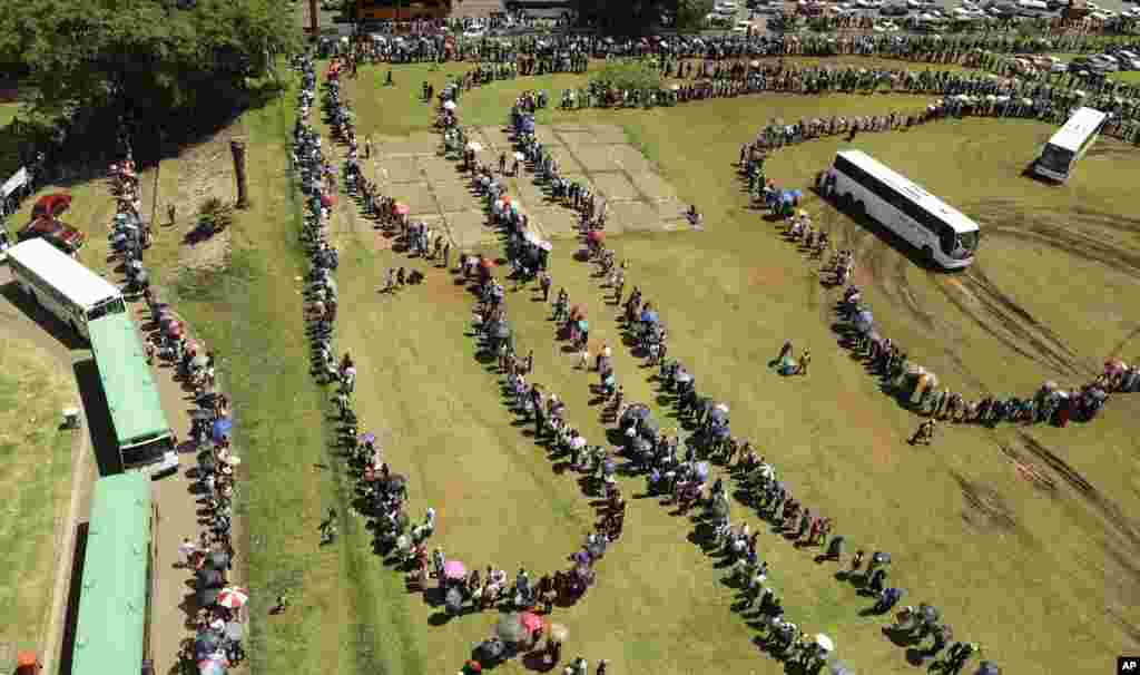 People line up to catch a bus to see the remains of Nelson Mandela at the Union Buildings in Pretoria, Dec. 12, 2013.