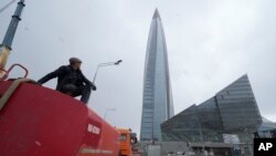 FILE - A worker sits on his water tank truck next to the business tower Lakhta Centre, headquarters of Russian gas monopoly Gazprom in St. Petersburg, Russia, April 27, 2022.