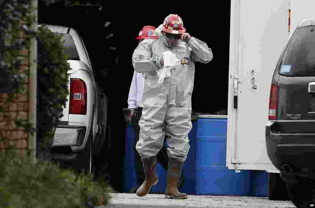 A worker wears a hazard suite in a staging area at a health care worker's apartment, who tested positive for Ebola in Dallas, Oct. 13, 2014.