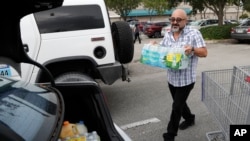 Alvaro Figueroa memasukkan air minum kemasan ke dalam kendaraannya untuk persiapan menghadapi Badai Dorian, di Hialeah, Florida, 29 Agustus 2019. 