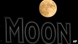 ARCHIVO - La luna se eleva más allá de un letrero en el estadio durante la quinta entrada de un partido de béisbol entre los Kansas City Royals y los Chicago White Sox en agosto de 2022, en Kansas City, EEUU.