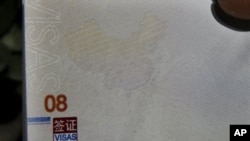有人在北京辦理護照的機構外面手持新護照，上面的地圖顯示南中國海屬於中國