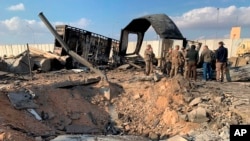 Vojnici SAD i novinari stoje pored kratera nastalog tokom iranskog bombardovanja, u Al Asad vazdušnoj bazi, Anbar, Irak, 8. januara 2020.