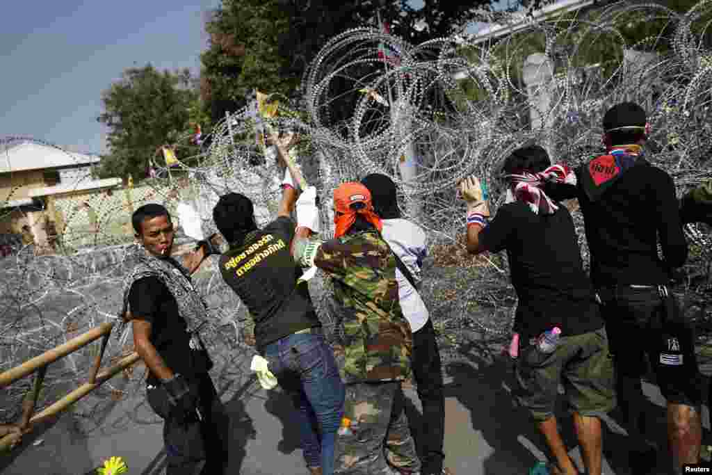 Anti-government protesters remove barbed wire after briefly entering the compound of the prime minister's office, known as Government House, in Bangkok, Dec. 12, 2013.