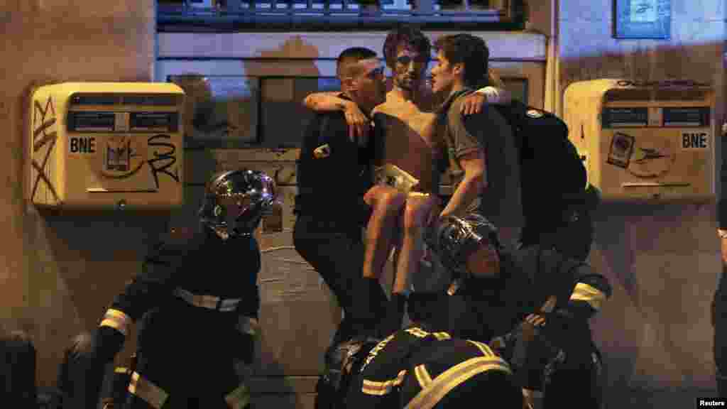 Des sapeurs-pompiers portent un blessé après les attaques terroristes simultanées qui ont fait au moins 129 morts à Paris, France, 13 novembre 2015.