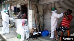 A health worker collects a nasal swab sample of a resident to test for test for COVID-19 in a slum area in Mumbai, India, Sept. 5, 2020.