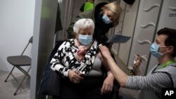 FILE - A woman receives a dose of the AstraZeneca COVID-19 vaccine at the Vaccine.