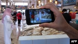 Seorang pemain game menggunakan apliksi Pokemon Go di perangkat telepon pintarnya di pasar ikan utama (14/7). Kuwait City, Kuwait. (foto: AFP Photo / Yasser Al-Zayyat)