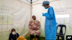 Une femme avec son enfant vont se faire tester pour le coronavirus au nord de Johannesburg, Afriquique du Sud le 8 mai 2020.