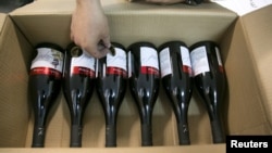 FILE - A worker places stickers on wine bottles while packaging them for export at Shiloh Wineries, north of the West Bank city of Ramallah, Nov. 8, 2015.