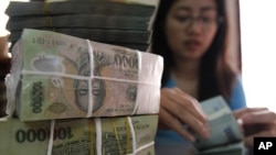 A woman counts Vietnamese dong bank notes in the office of a local company in Hanoi (File)