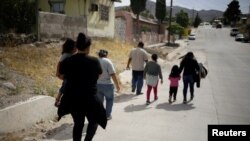 ARCHIVO - Una migrante hondureña junto a su hija caminan después de haber sido deportadas de Estados Unidos hacia Ciudad Juárez, en México. 22 de junio de 2020.