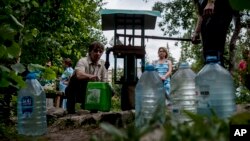 Warga lokal antri untuk mengumpulkan air di jalanan di pusat kota Slovyansk, Ukraina timur. (foto: AP Photo/Evgeniy Maloletka)
