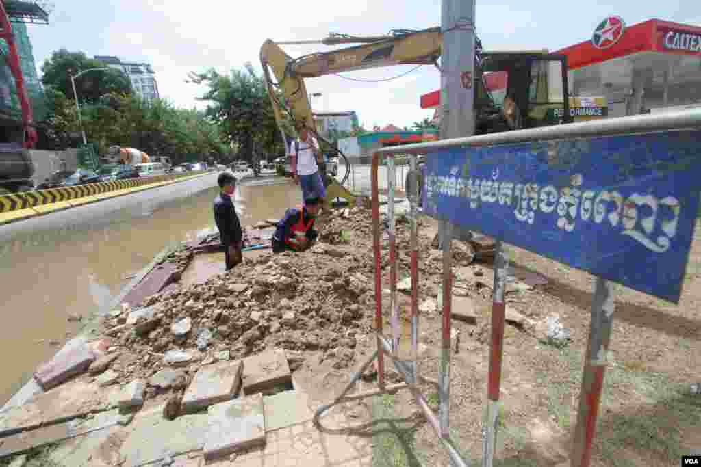 ក្រុមការងាររដ្ឋាករទឹកជួសជុលប្រព័ន្ធទឹកស្អាតបន្ទាប់ពីរថយន្តអេស្កាវេទ័រជីកកកាយដីប៉ះប្រព័ន្ធទុយោបណ្ដាលឲ្យធ្លាយទឹកបាចសាចចេញក្រៅនៅព្រឹកថ្ងៃអាទិត្យ ទី១៤ ខែសីហាឆ្នាំ២០១៦។ក្រុមការងារនៃមន្ទីរសាធារណៈការនិងដឹកជញ្ជូនជួសជុលបង្គោលភ្លើងនៅស្តុបបូកគោ នៃខ័ណ្ឌចំការមន រាជធានីភ្នំពេញ។(ឡេង ឡែន/VOA )